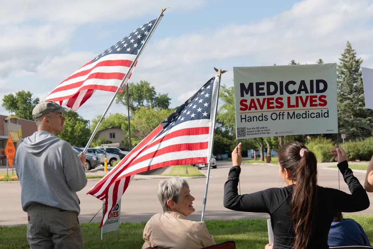 Residents hold American flags and a "Medicaid Saves Lives" sign at the Good Trouble rally in Brookings, South Dakota.